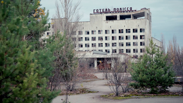 CHERNOBYL, UKRAINE - NOVEMBER 6, 2019: firs near abandoned building with hotel polissya lettering  - Кадри, відео