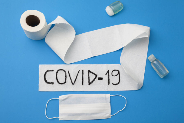 coronavirus focolaio covid 19 scritto su un rotolo di carta igienica, disinfettanti per le mani, maschera facciale monouso su sfondo blu
. - Foto, immagini