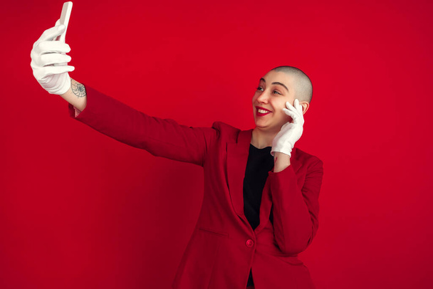 Portrait of young caucasian bald woman on red background - 写真・画像