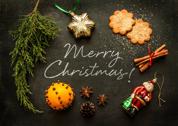 Merry Christmas - poster or postcard design. Vintage decorations, ginger cookies and spices on black chalkboard from above. - Fotó, kép