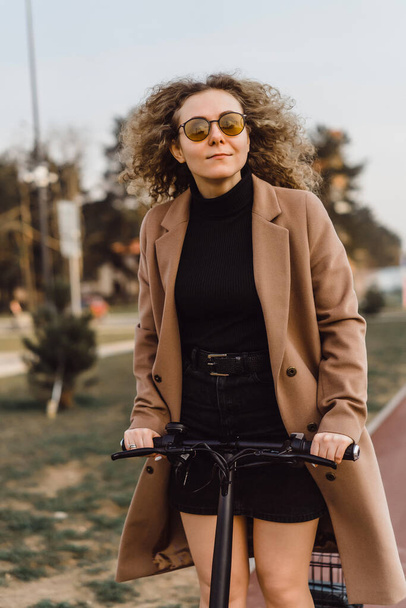 Young beautiful woman riding an electric scooter to work, modern - Foto, imagen