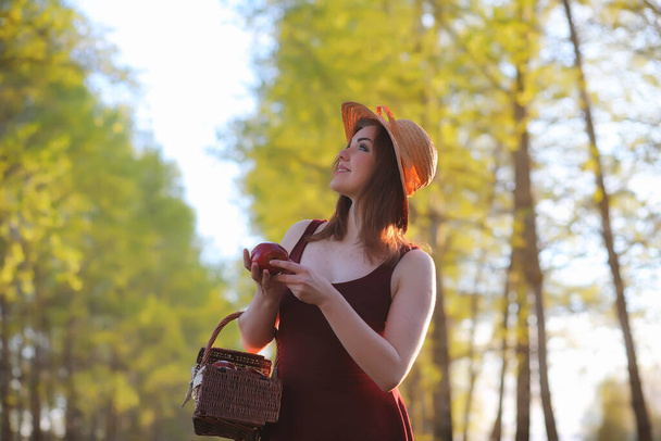 A girl in a hat on a walk in the park. A girl with a basket walks in the spring. Girl is walking along the road at sunset - Fotó, kép