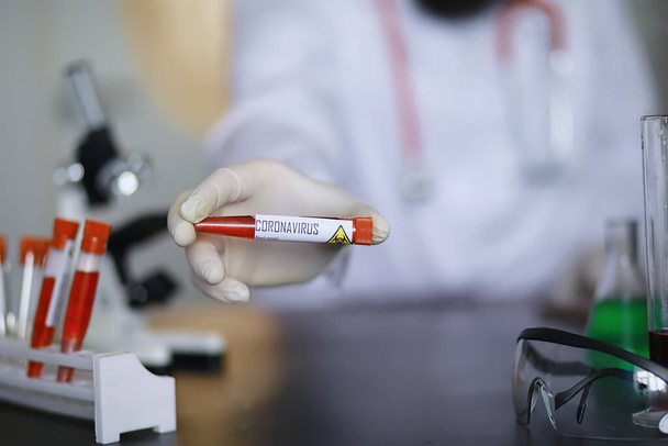 Ένας επιστήμονας ερευνητής στο εργαστήριο δοκιμάζει φάρμακα για τη θεραπεία της ιογενούς πνευμονίας. Εξέταση αίματος κορονοϊού μολυσμένων ασθενών. Παγκόσμια πανδημία. - Φωτογραφία, εικόνα