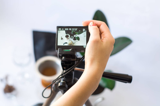 Aufnahme von Video mit der Kamera auf Stativ der Kaffeezubereitung auf weißem Hintergrund. - Foto, Bild