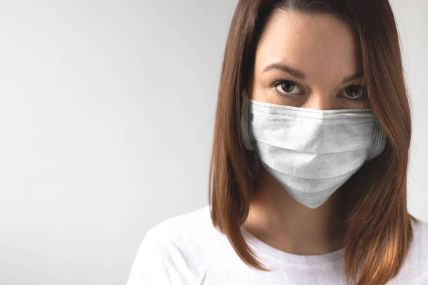 Coronavirus concept. Meisje met een beschermend medisch masker. Bescherm je gezondheid. Stop het virus en pandemische covid-19. Lichtgrijze achtergrond - Foto, afbeelding