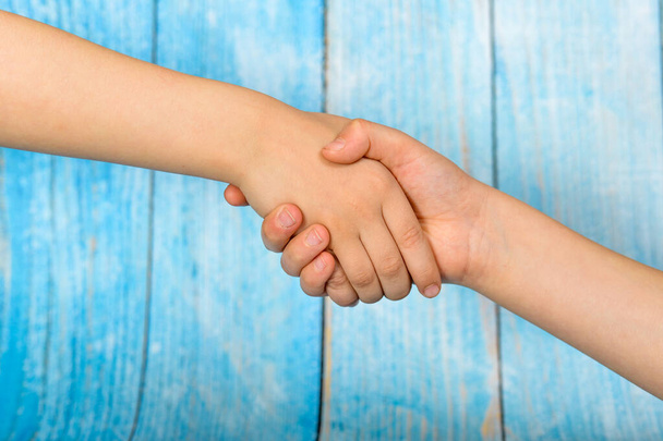 Дружелюбные люди пожимают руки на синем деревянном фоне
 - Фото, изображение