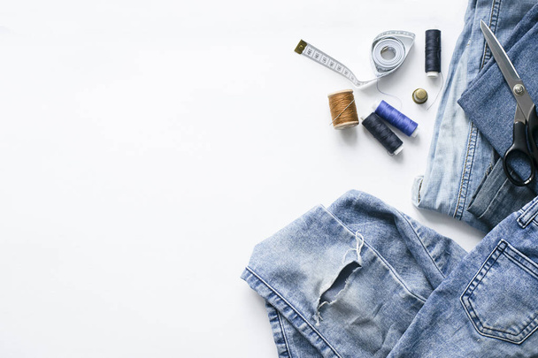 Handicraft, clothing repair. Ripped blue jeans sewing accessories white background. The concept of economical things. - Φωτογραφία, εικόνα