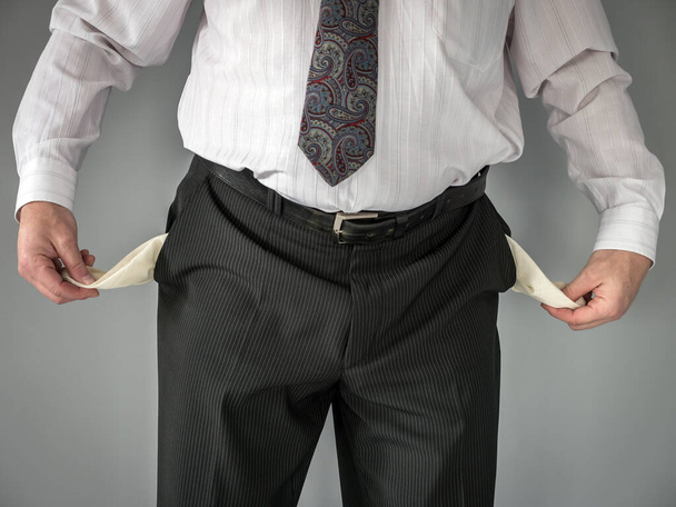Szekrény üzletember bemutató üres nadrág zsebek felett szürke háttér - Fotó, kép