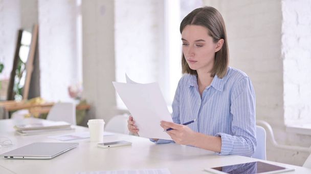 Fleißige junge Frau liest Dokumente im Büro - Foto, Bild