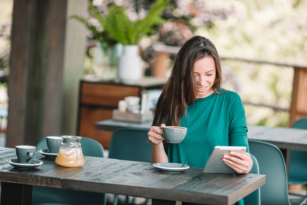 Jonge vrouw met smartphone tijdens het zitten alleen in de coffeeshop tijdens vrije tijd - Foto, afbeelding