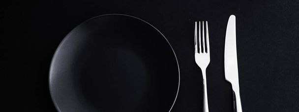 Empty plates and silverware on black background, premium tableware for holiday dinner, minimalistic design and diet - Photo, Image
