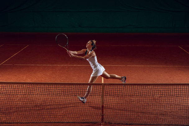 Young caucasian professional sportswoman playing tennis on sport court background - Foto, afbeelding