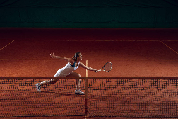 Young caucasian professional sportswoman playing tennis on sport court background - Zdjęcie, obraz