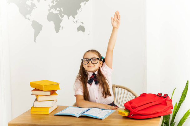 Joyeux petit étudiant avec des lunettes avec carnet ouvert tire une main avec au bureau dans la salle de classe. Concept d'éducation
 - Photo, image