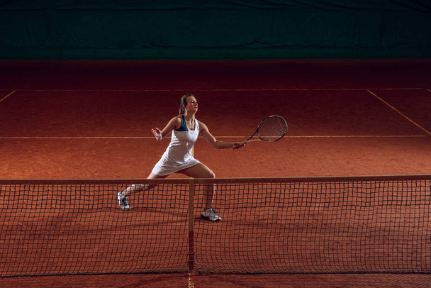 Young caucasian professional sportswoman playing tennis on sport court background - Foto, immagini