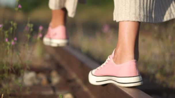Egy lány sétál a vasúti síneken. Romantikus lassított felvétel fiatal lányok lábáról közelkép séta a vasúti sín mentén nyáron. - Felvétel, videó