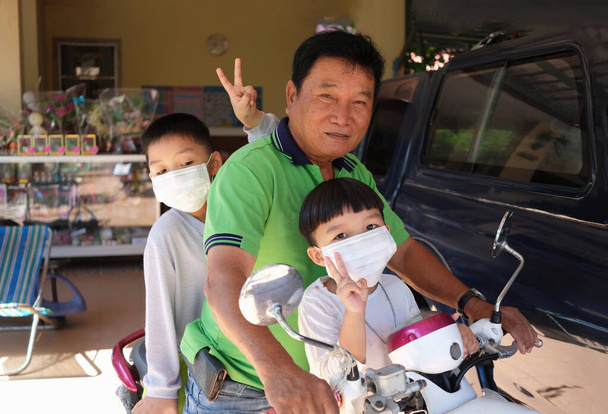 Grand-père a pris deux petits-fils aller au marché et porter des masques blancs protection
 - Photo, image