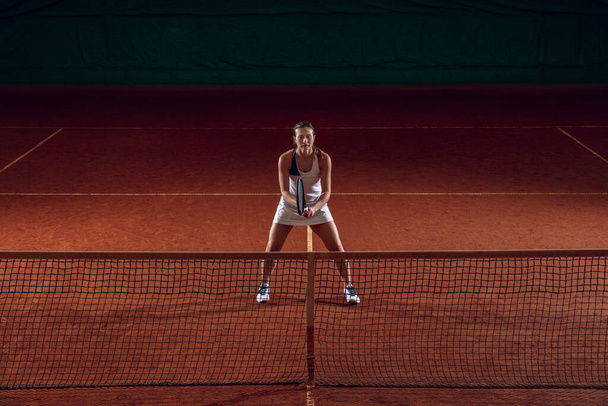 Young caucasian professional sportswoman playing tennis on sport court background - Foto, imagen