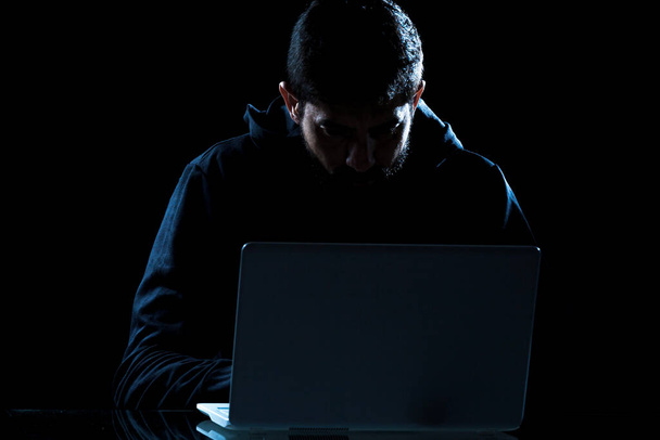 Dramatic shot of hacker using laptop in dark room - Foto, Imagen