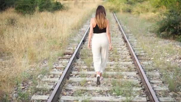  Trendy νεαρή γυναίκα με τα πόδια στις σιδηροδρομικές γραμμές. - Πλάνα, βίντεο