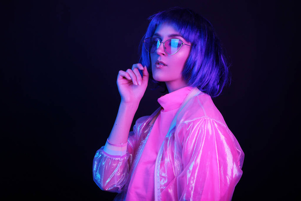 Neon light studio close-up portrait of happy woman model in a wig in sunglasses. Nightlife, party in a nightclub. Copy space. - 写真・画像