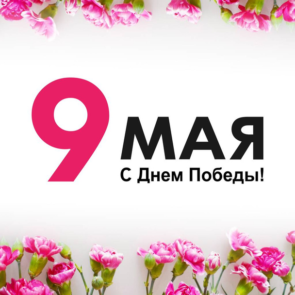 Pozdrav na Den vítězství. Čtvercová fotka s rámečkem růžových karafiátů na bílém pozadí. Text v ruštině: 9. května, Gratulujeme k vítězství! - Fotografie, Obrázek