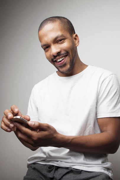 Happy black guy in white T-shirt posing in the studio. Vertical. - Zdjęcie, obraz