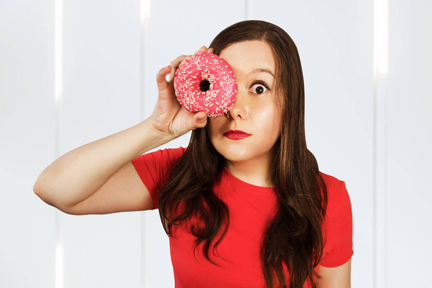 Beautiful girl holding pink donut an having fun. - Foto, imagen