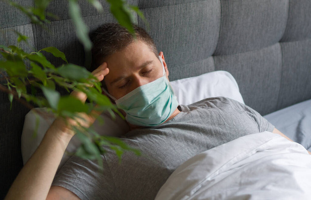 Хвора людина з медичною маскою лежить у ліжку. Концепція карантину коронавірусу
. - Фото, зображення