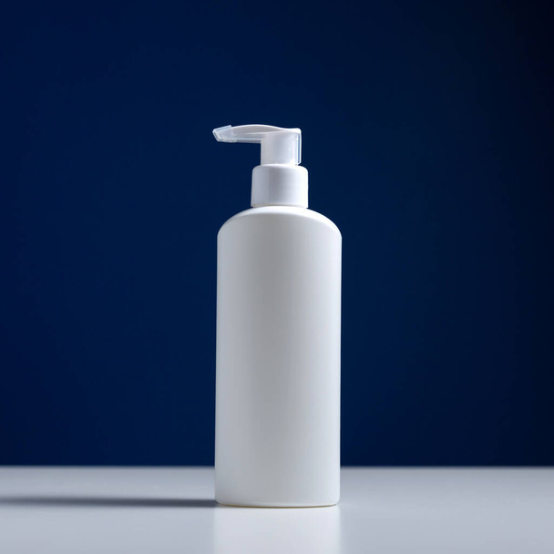 Plastic white antiseptic bottle with a dispenser on a blue background. - Photo, image