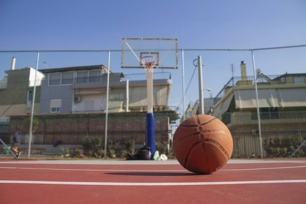 Використана баскетбол на передньому плані лежить на баскетбольному майданчику і баскетбольний баскетбол з розмитим тлом
 - Фото, зображення