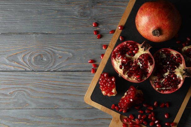 Board with pomegranate on wooden background, top view - Zdjęcie, obraz
