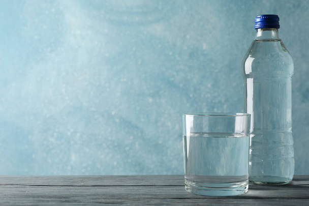 Flasche mit Wasser und Glas auf Holztisch, Platz für Text - Foto, Bild