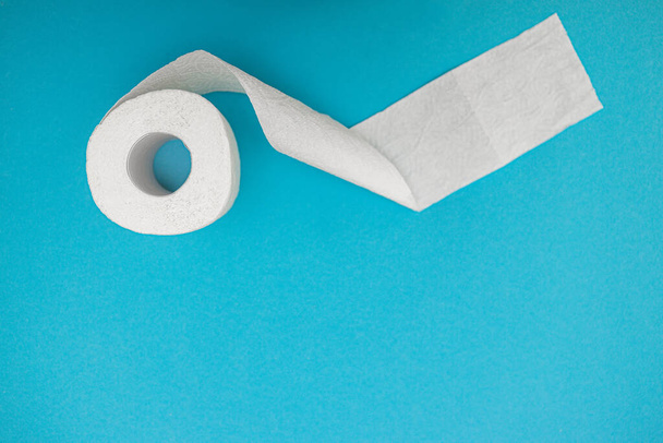 Un rollo de papel higiénico blanco sobre un fondo azul. Vista desde arriba. Copiar espacio
. - Foto, Imagen