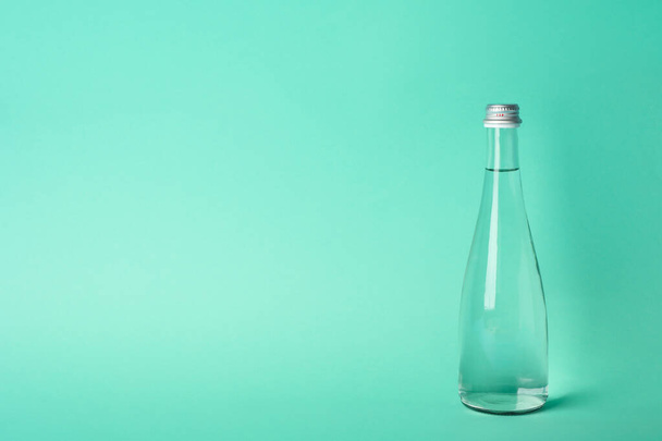 Bottle with water on mint background, space for text - Фото, изображение