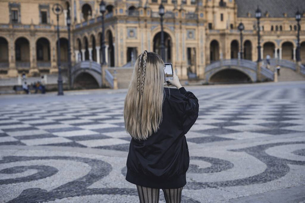 A young female taking a photo of the famous Plaza of Spain in Sevilla - Zdjęcie, obraz