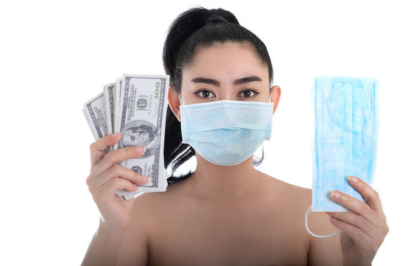 Blisko ręce trzymając medyczną maskę ochrony przed wirusami i pieniędzy 100 dolarów banknotu dużo na czarnym tle, To kosztuje drogie produkty wysokiej cenie i sprzedaje kupić medyczne maski koncepcja - Zdjęcie, obraz