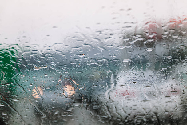 Provoz se zastavil, za chladného, vlhkého dne, proletěl čelním sklem a soustředil se na kapky deště, rozostřená světla. Pohled z okna auta. Konceptuální špatné počasí pozadí. - Fotografie, Obrázek
