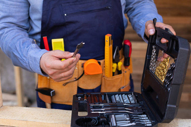 Close up picture of carpenters tool belt and work instruments on wooden background - Photo, Image