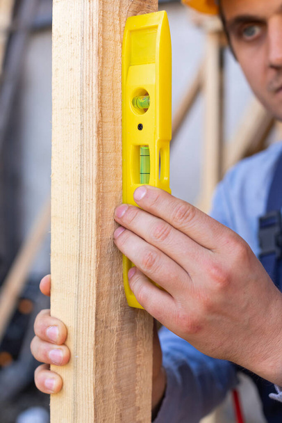 Close up picture of carpenter holding spirit level measuring lumber - Φωτογραφία, εικόνα