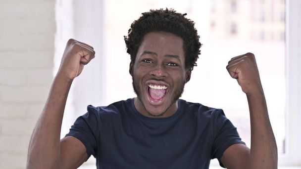 Portrait d'un homme afro-américain ambitieux célébrant avec les deux poings
 - Photo, image