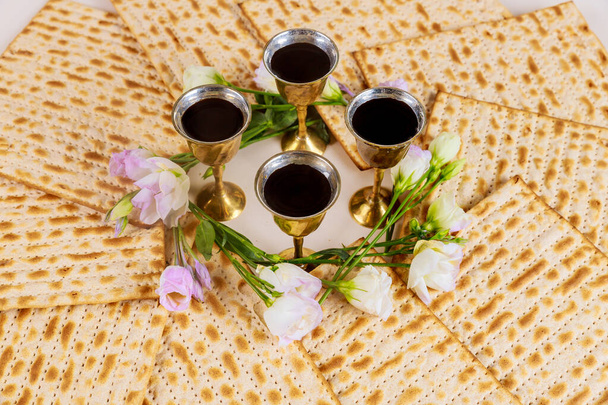 Cuatro copas de vino con matzá y flores. Vacaciones judías Concepto de Pascua
. - Foto, Imagen
