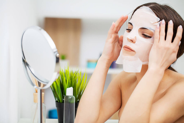 Pretty girl wearing face care mask at home - Foto, Bild