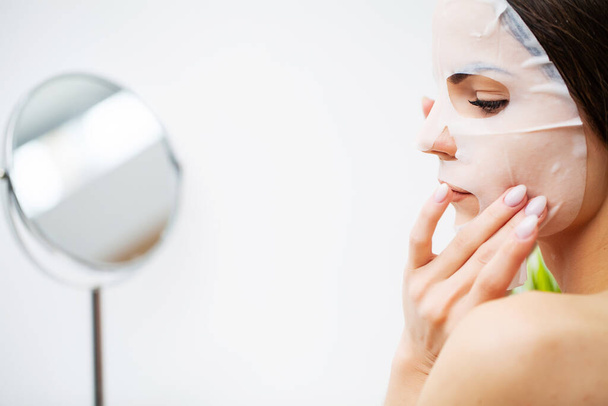 Žena používá masku na péči o obličej v koupelně - Fotografie, Obrázek