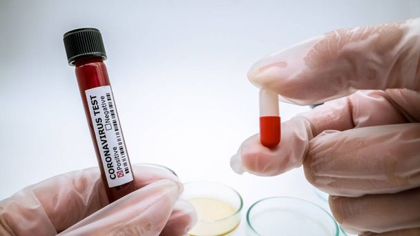 Novel coronavirus pill and blood test tube on white background. Covid-19 is currently trying to find a drug against the virus to treat the infected. Pills to cure 2019-nCoV concept. - Photo, Image
