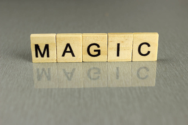 palabra magia, hecha de letras cuadradas de madera sobre un fondo gris
 - Foto, Imagen