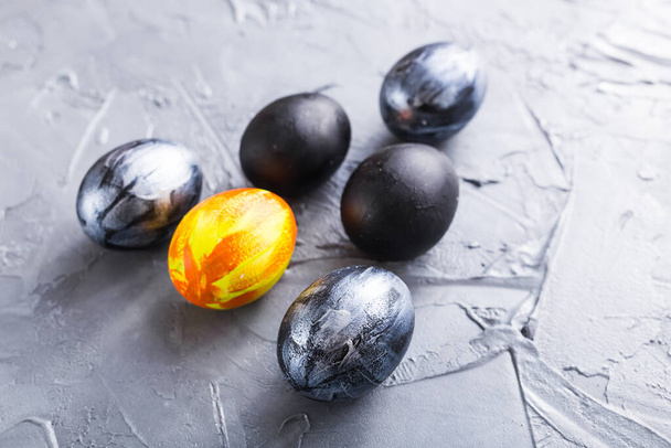 Vacaciones, tradiciones y concepto de Pascua - Huevos de Pascua con estilo oscuro sobre fondo gris
. - Foto, Imagen