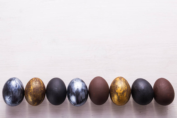Férias, tradições e conceito de Páscoa - Ovos de páscoa elegantes escuros em fundo de madeira branca com copyspace
. - Foto, Imagem