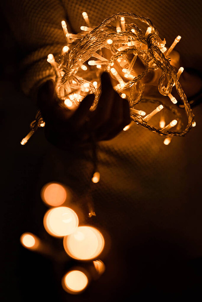 Dziewczyna trzyma rząd migających świateł girlandowych. Koncepcja Wigilii. Szczęśliwego Nowego Roku. - Zdjęcie, obraz