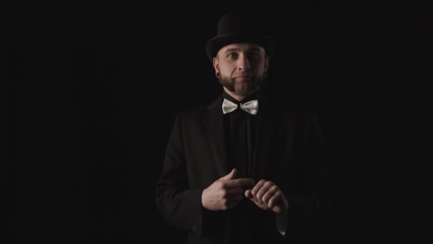 Magician gets a flower from nowhere. Look serious at camera. Black background low key - Footage, Video